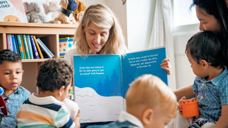 Woman reading a picture book to children