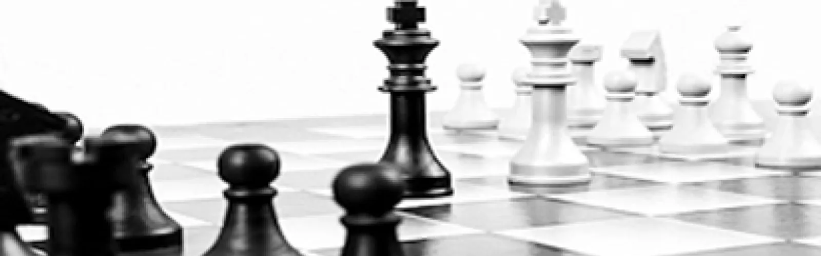 Black and white chess pieces set up on a chessboard.