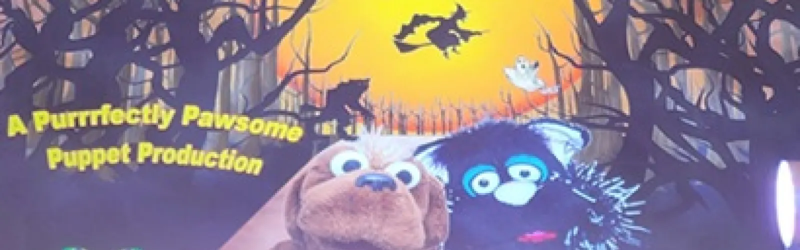 A spooky Halloween background with a black cat and brown dog puppets in front.